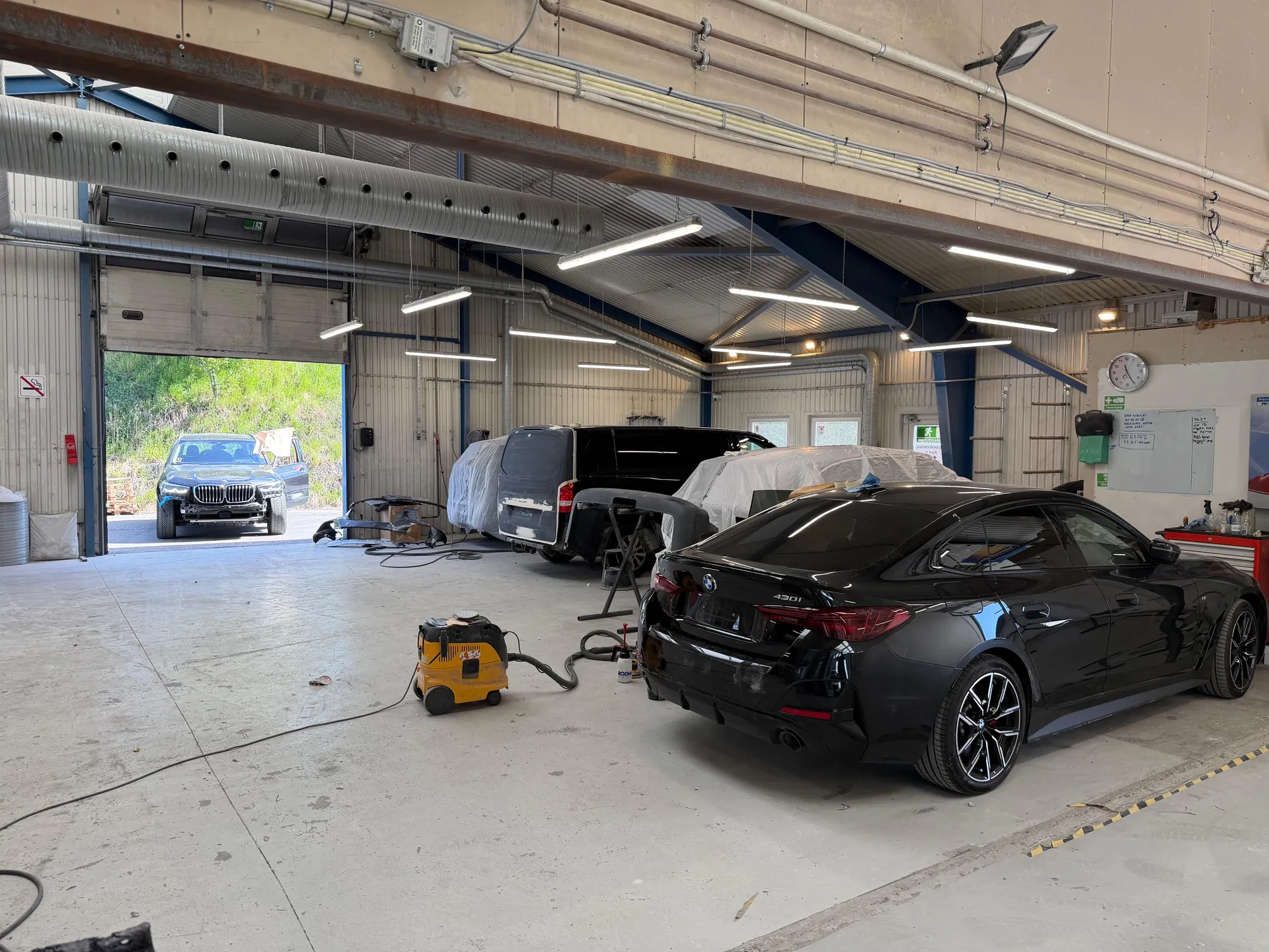 Clean workshop, BMWs, bay door open — facility scale